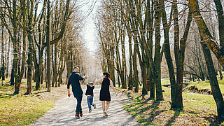 Eltern die mit ihrem Kind im Park spazieren gehen