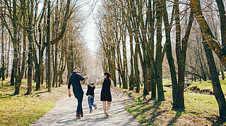 Eltern die mit ihrem Kind im Park spazieren gehen