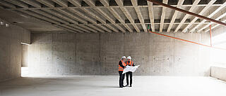 zwei Bauplaner in einer leeren Halle