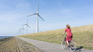Person die mit dem Fahrrad neben Windrädern vorbei fährt