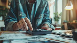 Mensch tippt auf einem Taschenrechner